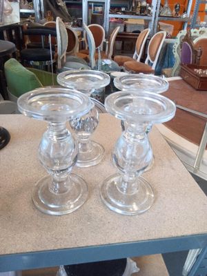 quatre bougeoirs en verre posés sur une table dans un magasin