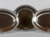 three silver plated dishes on stands on a white surface