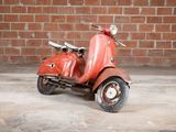 a red scooter that is parked in front of a brick wall