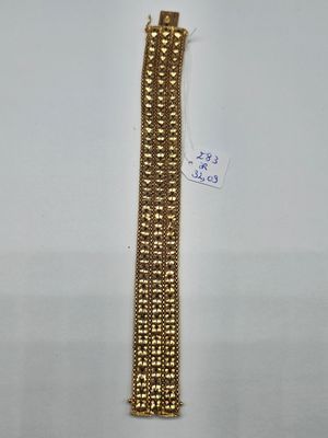 gros plan d'un bracelet en or sur une surface blanche