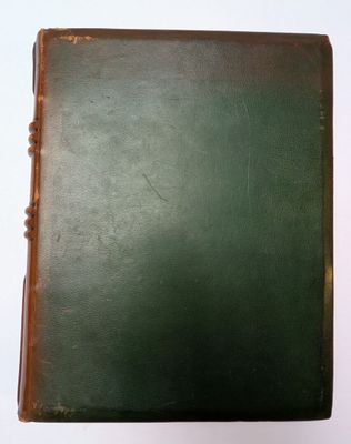 un vieux livre posé sur une table blanche à côté d'un mur blanc
