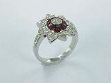 gros plan d'une bague en diamant et rubis sur une surface blanche