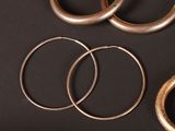 three pairs of gold hoop earrings on a black surface