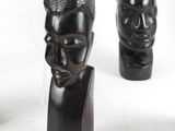 three wooden sculptures of a man ' s head and a woman ' s head on a white surface