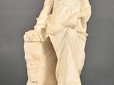 statue d'une femme assise sur un rocher, un panier à la main