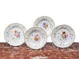 four plates with flowers on them are sitting on a table
