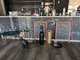 bottles of wine and bottles of wine on a bar with a chalkboard behind them