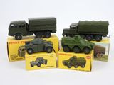 quatre véhicules militaires miniatures dans leurs boîtes, posés sur une surface blanche