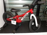 un vélo rouge et blanc exposé devant la porte d'un garage