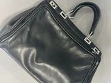 black leather handbag with silver metal handles on a white surface