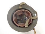 an old military helmet is sitting on a stand on a white surface