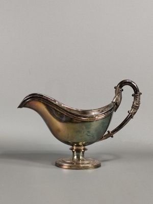 an antique silver plated sauce boat on a stand
