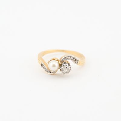 un gros plan d'une bague en or sertie de deux diamants et d'une perle