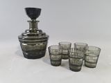 des bouteilles et des verres posés à côté d'une carafe sur une surface blanche