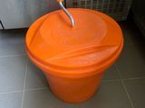 un seau orange posé par terre devant un réfrigérateur