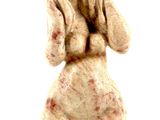 une petite statue représentant un chien assis sur une surface blanche
