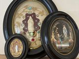 three framed pictures on a shelf next to a clock
