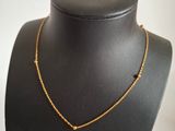 a black mannequin with a gold necklace on it