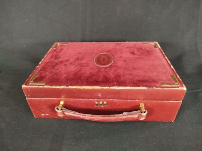 une vieille valise rouge posée sur une surface noire