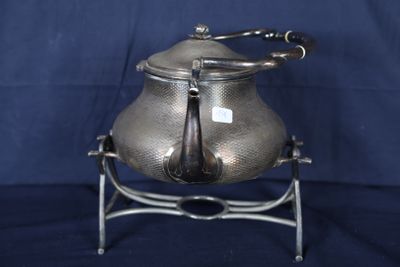 une théière en argent posée sur un socle, sur un fond bleu