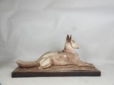 statue of a dog laying down on a wooden base