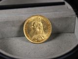une pièce d'or dans une boîte avec une loupe
