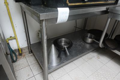 table en acier inoxydable sur laquelle sont posés des casseroles et des poêles, dans une cuisine professionnelle