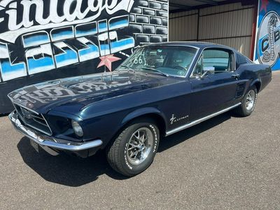 une photo d'une Mustang bleue garée devant un immeuble