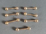 six pairs of gold plated nose studs on a gray surface