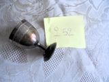 un petit verre à vin en argent sur lequel est posée une petite note
