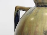 a blue and brown vase with a handle on a table