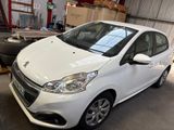 une voiture blanche garée dans un garage, à côté d'un tas de pneus