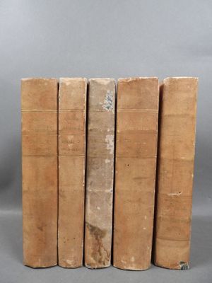 six old books stacked on top of each other on a gray surface