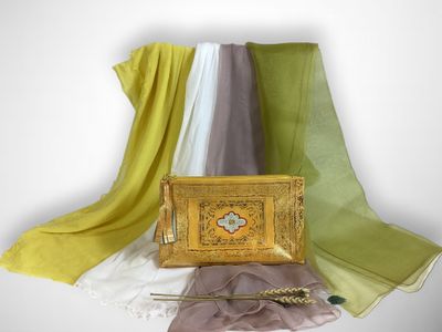 a gold purse sitting on top of a table next to a scarf
