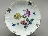 une assiette blanche ornée de fleurs, posée sur un socle