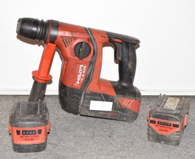 une perceuse filaire et deux batteries posées par terre