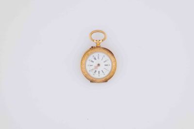 an old gold pocket watch with a white face on a white background