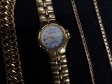 a gold watch with a chain around it on a black surface