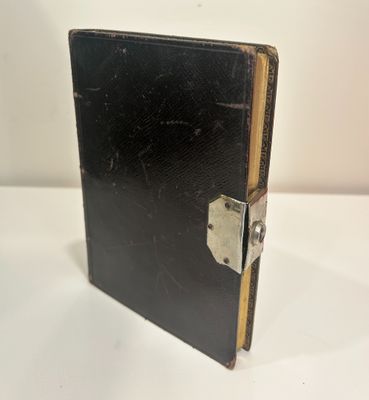 an old black book with a lock on it sitting on a table