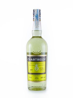 La bouteille de Chartreuse est posée sur une surface blanche.