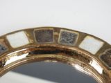 a mirror that has a gold frame with white and black squares