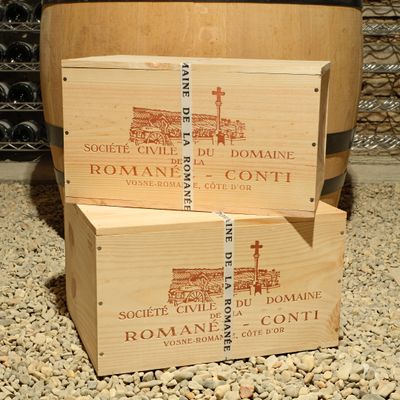 three wooden boxes stacked on top of each other in front of a barrel of wine