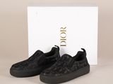une paire de baskets noires sans lacets devant une boîte blanche
