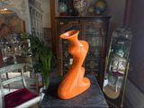 an orange vase sitting on top of a table in a room