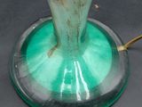 a glass vase with a green base on a table