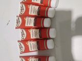 Plusieurs tubes de dentifrice sont alignés sur une surface blanche