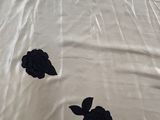a white sheet with black flowers on it on a bed