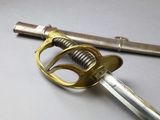 a sword with a gold handle on a white surface