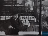 photographie en noir et blanc d'un homme assis à une table dans un restaurant