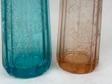 two different colored glass bottles sitting next to each other